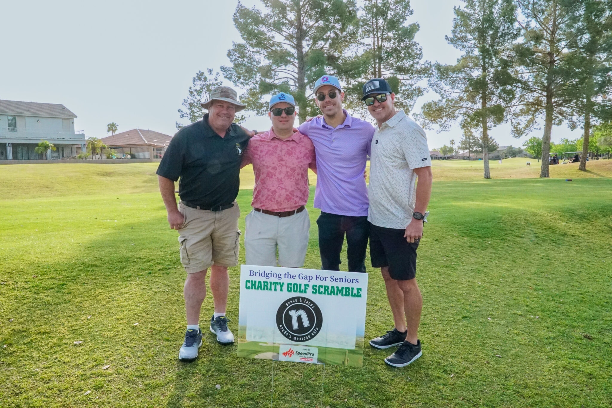 Team posing with the Bridging the Gap Charity Golf Scramble sign